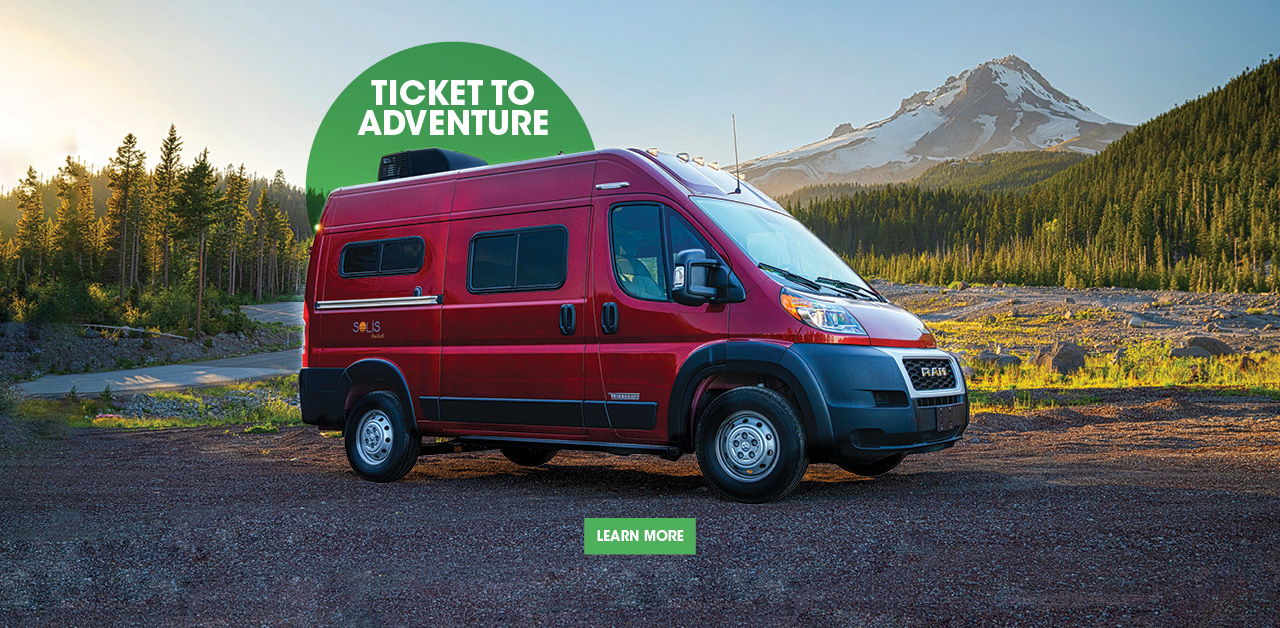 Red Winnebago Solis Pocket parked in picturesque mountainscape.